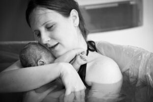 Mother holding her newborn baby in water immediately after birth